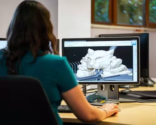 A woman working on a 3D model at a desk.